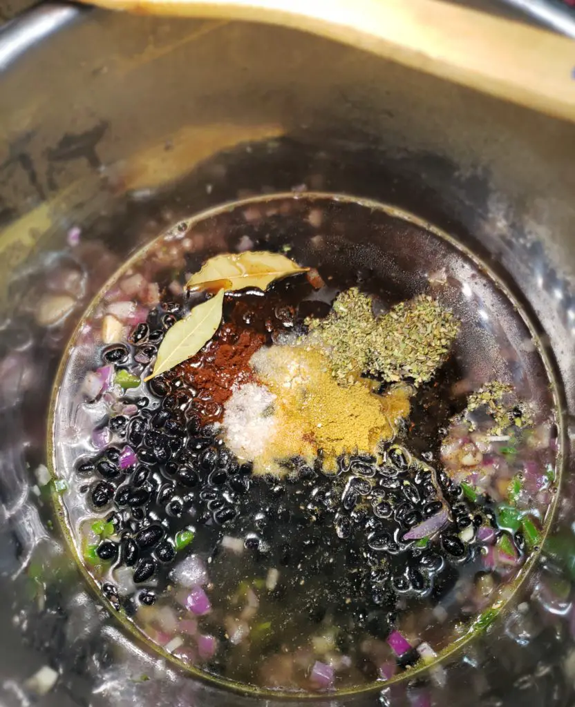 overheard image of instant pot containing dried black beans, cooking liquid and spices to make instant pot black bean recipe