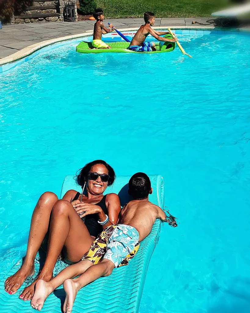 woman smiling and sharing pool float with little boy