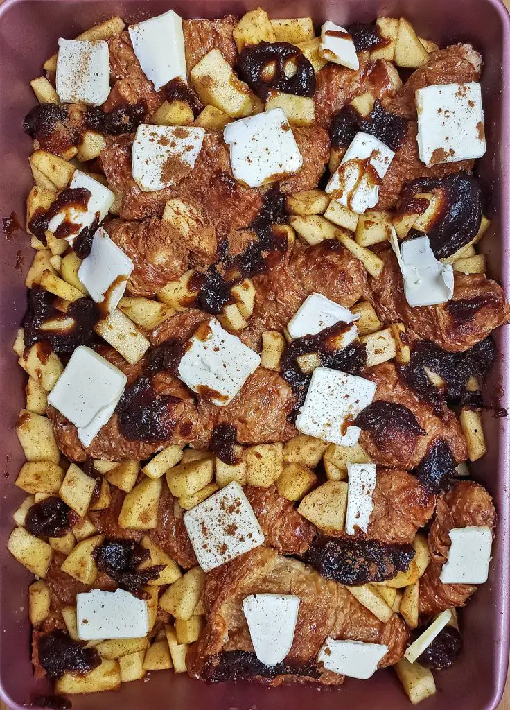 french toast in baking dish with apples, apple butter, cinnamon and butter slices