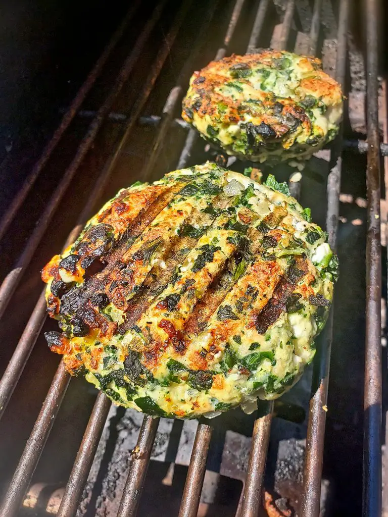 two spinach turkey burgers grilling on bbq grill