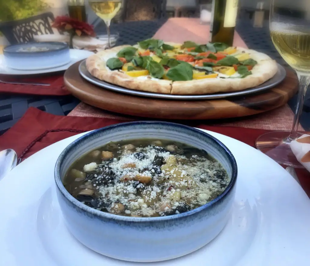"Swiss chard, potato soup with chickpeas" "caprese pizza" "white wine" "dinner on patio" "place stetting"