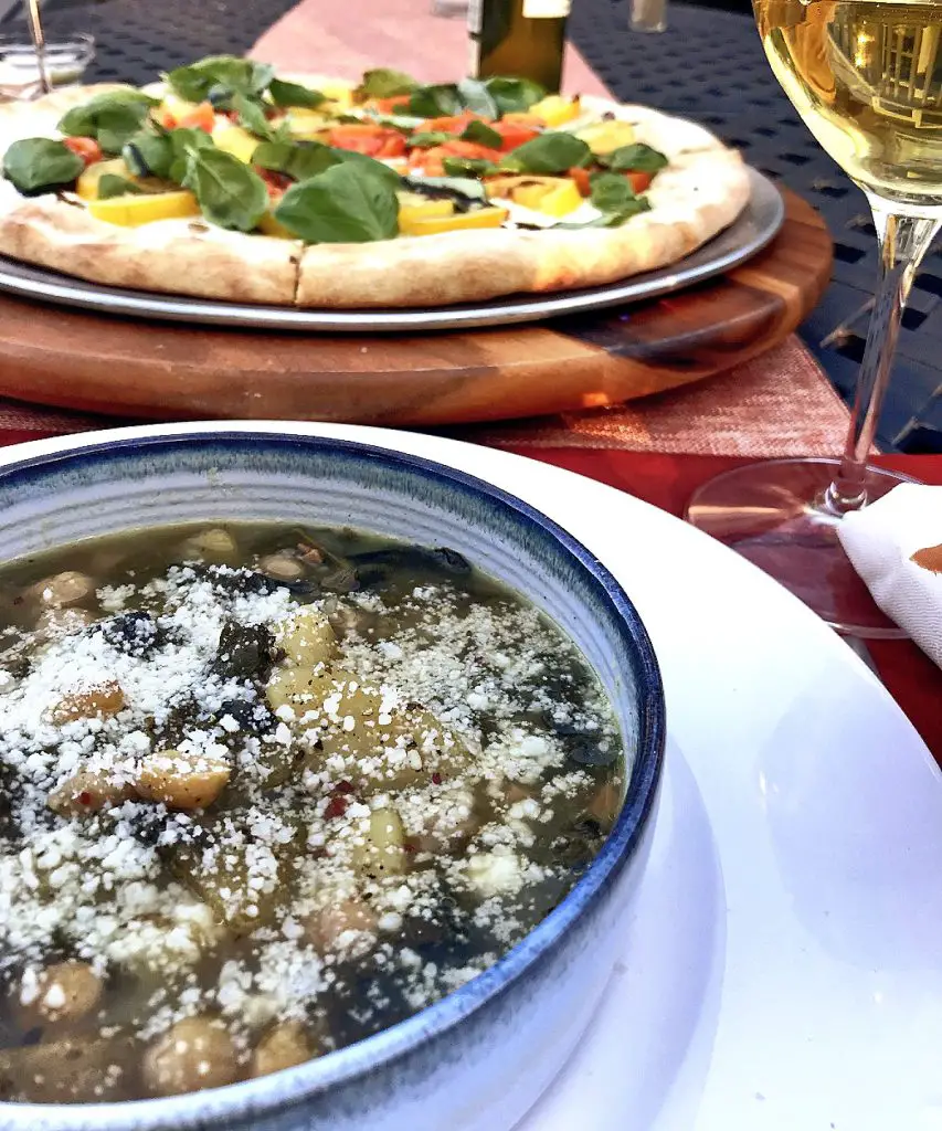 "Swiss chard, potato soup with chickpeas" "caprese pizza" "white wine" "dinner on patio" "place stetting"