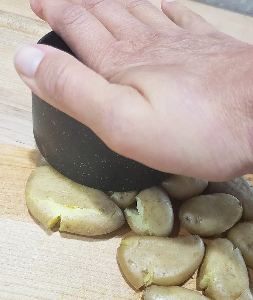 smash boiled baby potatoes with measuring cup