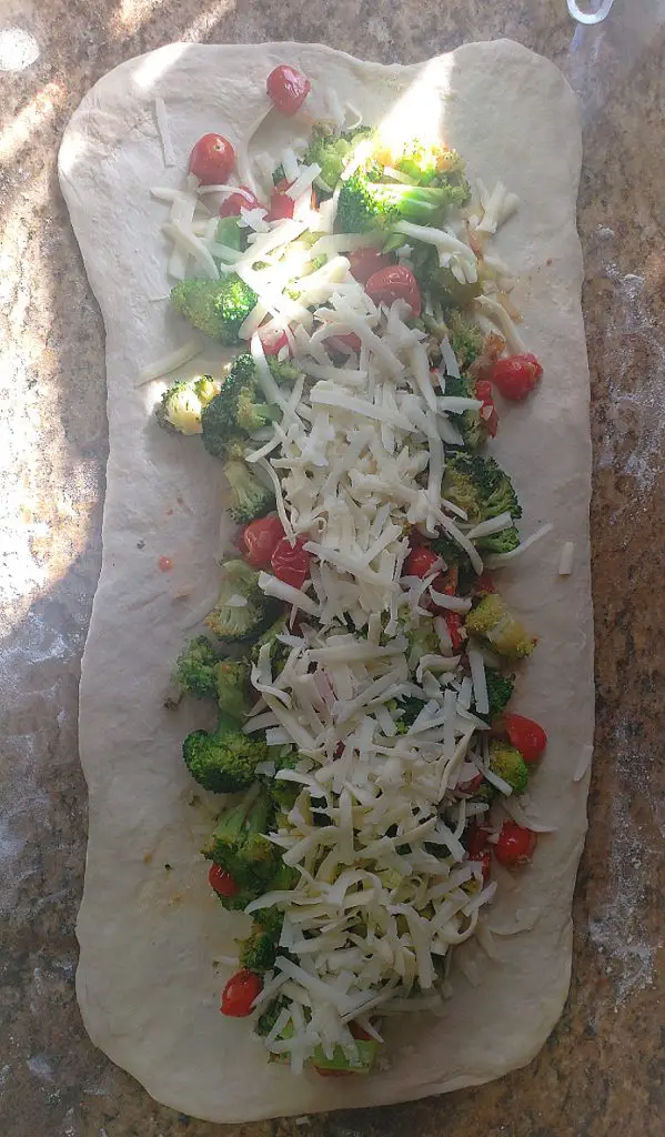 filling and cheese on rectangle shaped dough before rolling into stromboli