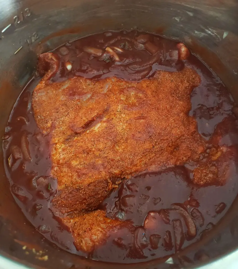 brisket partially submerged in sauce in an instant pot
