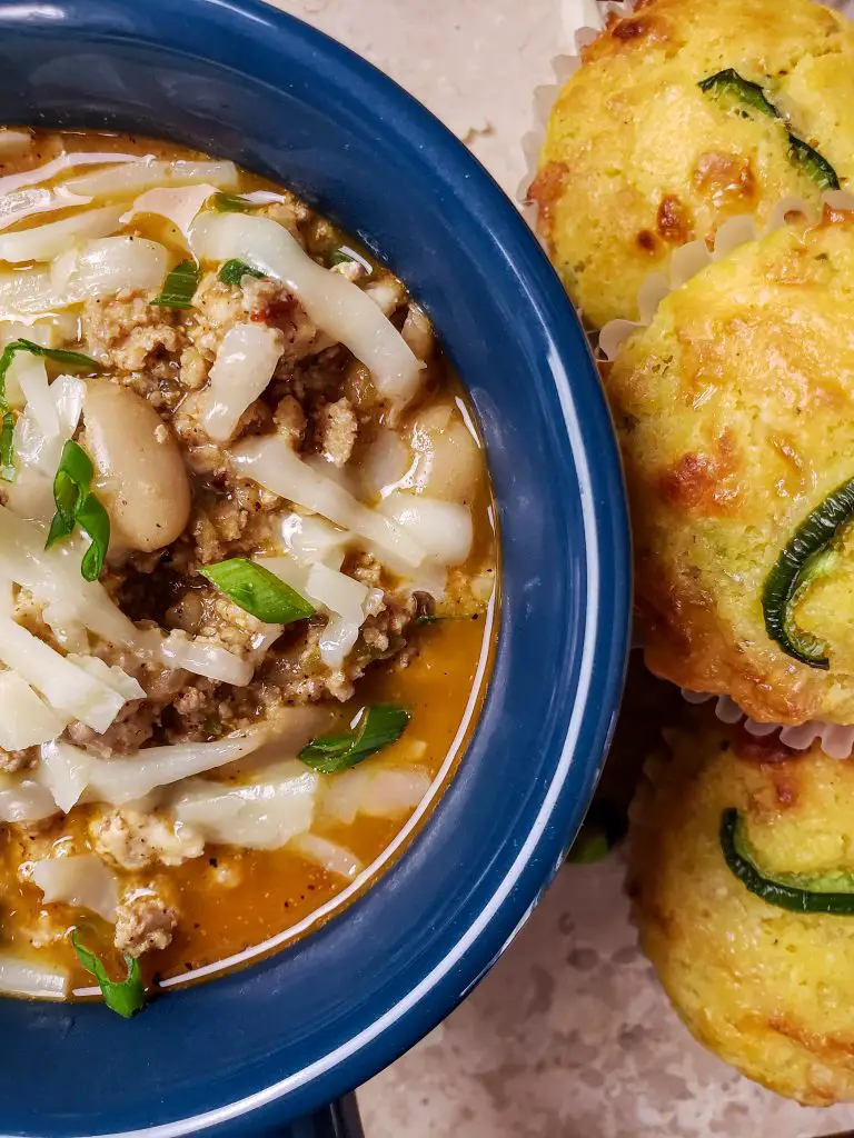 white bean turkey chili in blue bowl served with cornbread