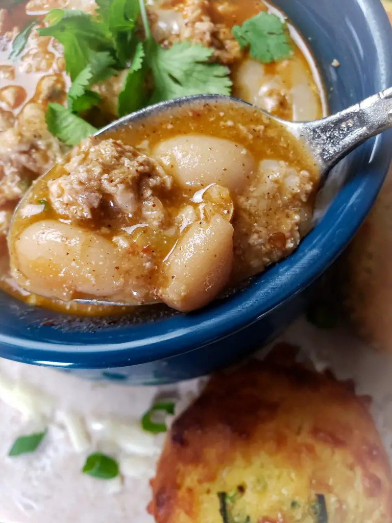 spoonful of white bean turkey chili in blue bowl served with cornbread