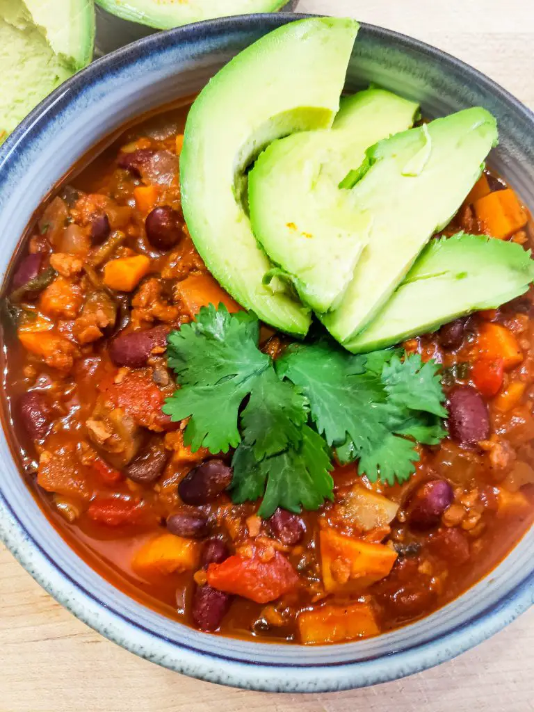 bowl of vegan chili with avocado slices
