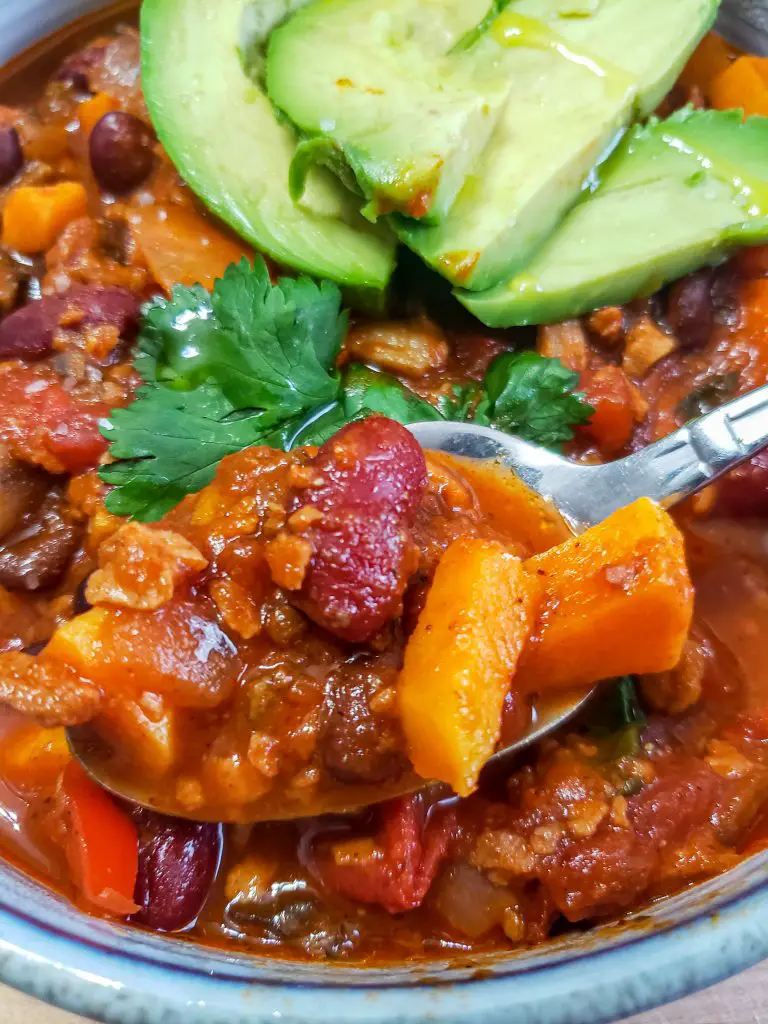 spoon of vegan chili with avocado slices