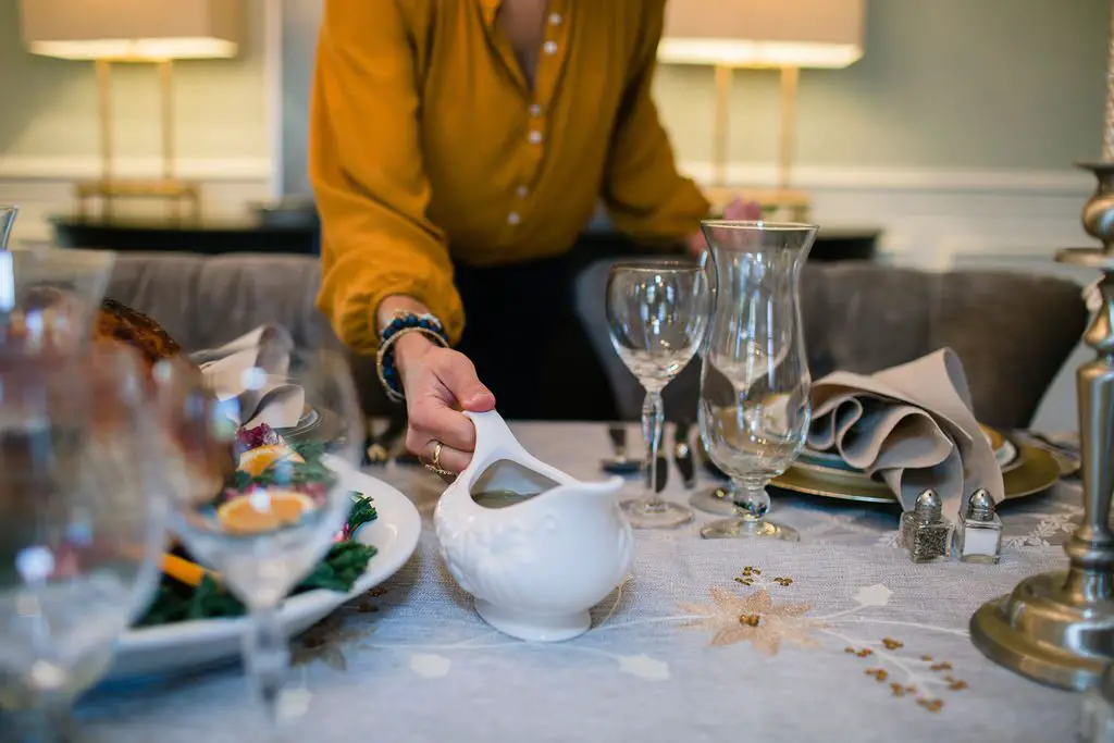 woman placing gravy boat on thanksgiving table