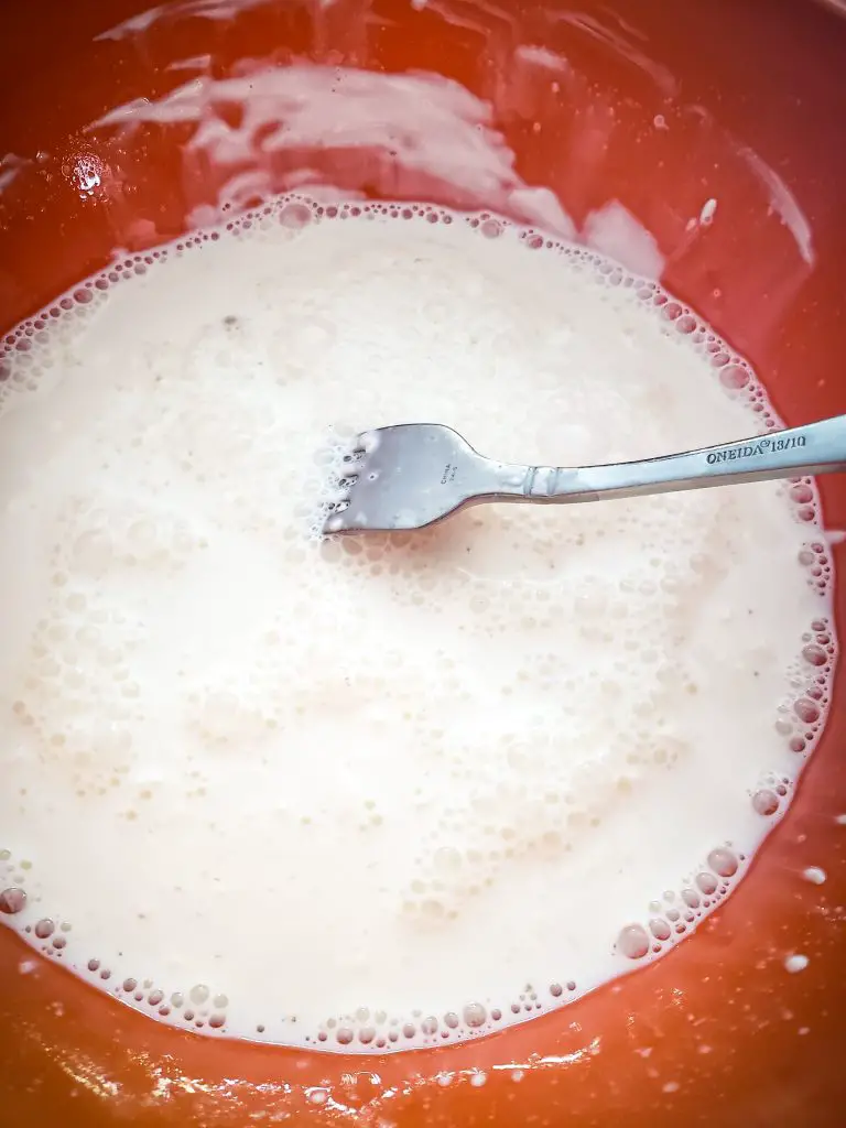 image of fork in mixing bowl of milk, spice and cheese to make lazy mom mac and cheese