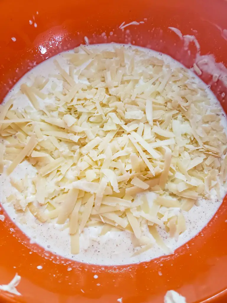 image of shredded cheese in mixing bowl with milk to make easy mac and cheese