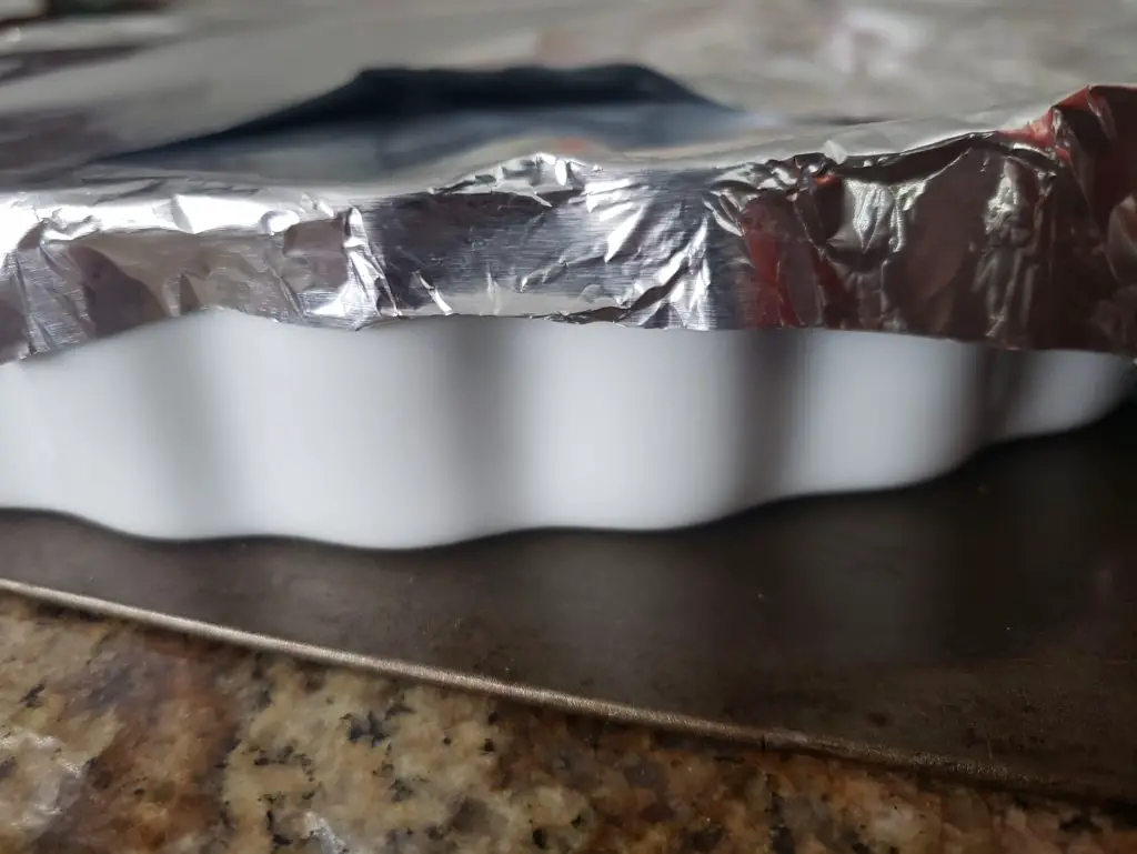side angle image of shallow baking dish covered with aluminum foil