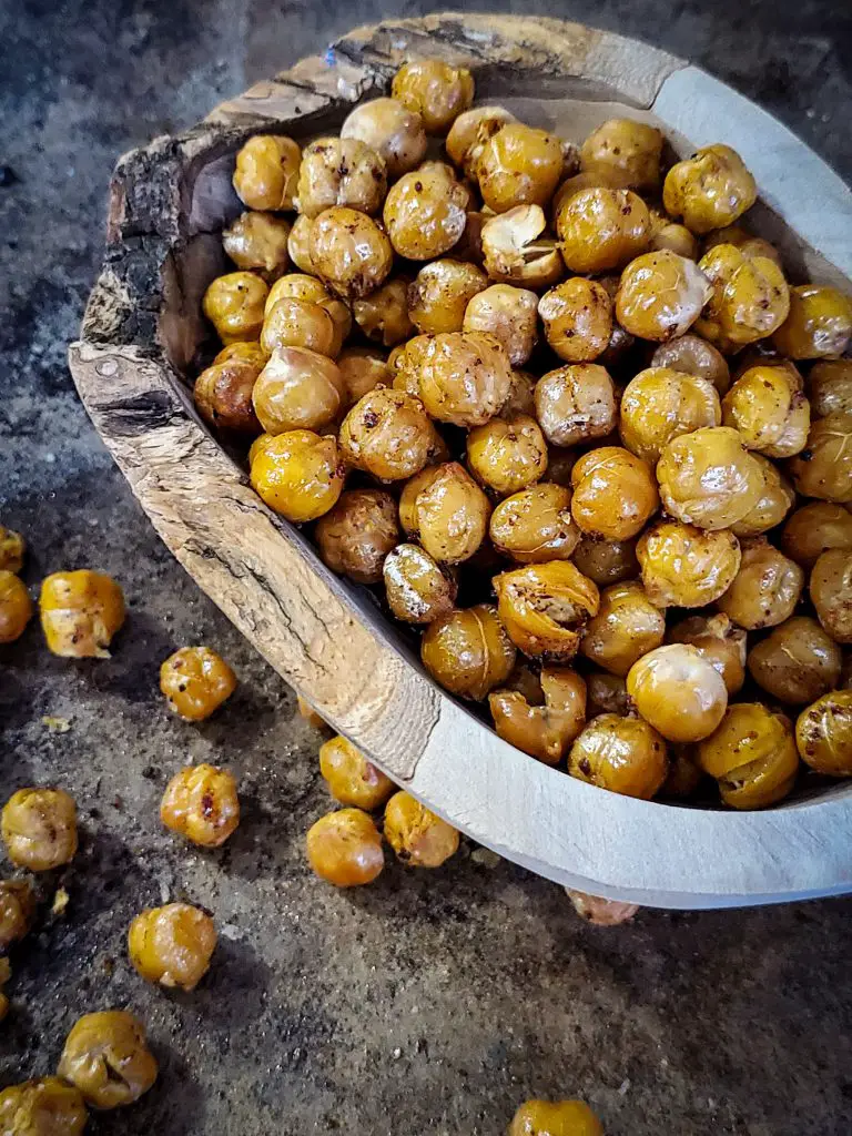 up close side angle image of wooden bowl of crisp chickpeas