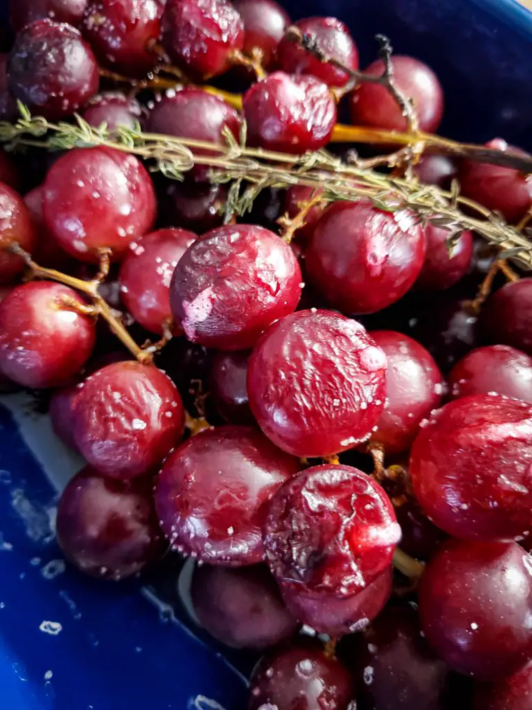 image of roasted grapes with fresh thyme sprigs on baking sheet
