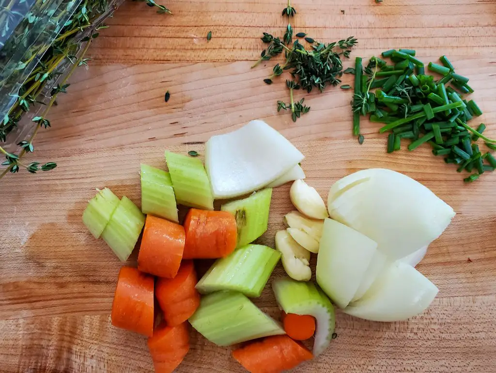 image of celery, carrot, onion , garlic, chives and thyme on cutting board