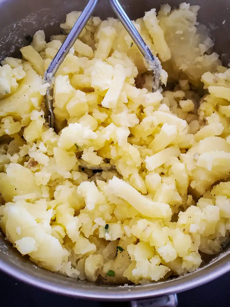 image of potato masher mashing potatoes in a pot