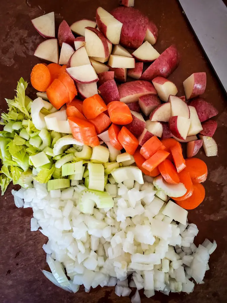 image of chopped onion, carrot, celery and potatoes on cutting board