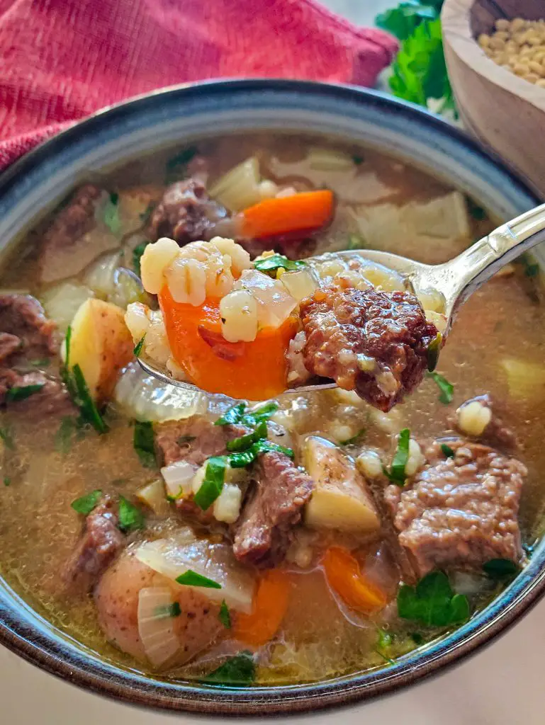 image of spoon holding bite of beef and barley soup