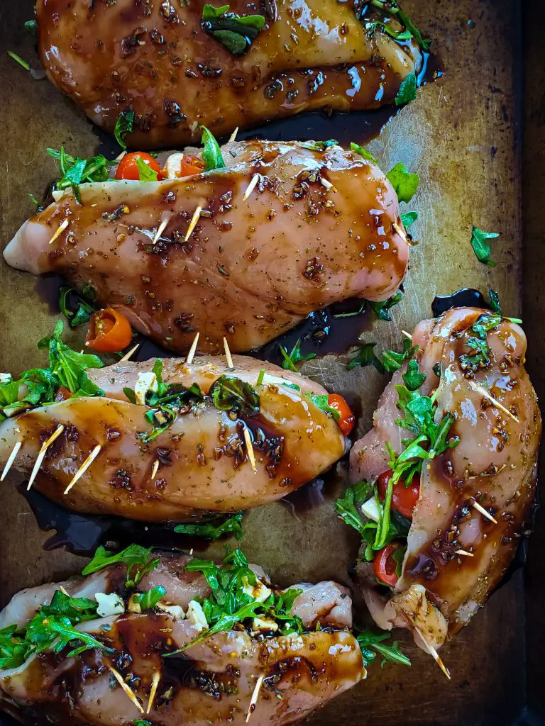 image of raw caprese stuffed chicken breasts with balsamic glaze topped on baking sheet