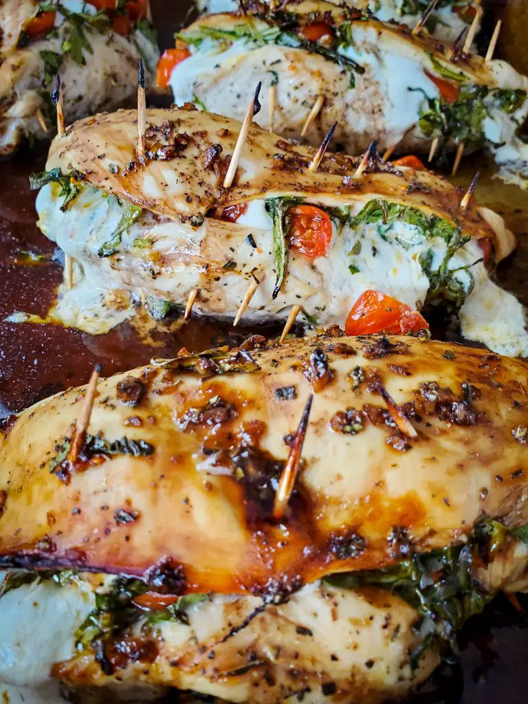 image of oven baked caprese stuffed chicken breasts with balsamic glaze secured with toothpicks