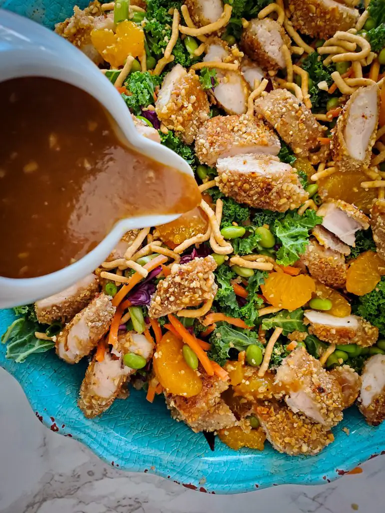 peanut ginger lime dressing poured over Chinese Salad with Peanut-Crusted Chicken Tenders