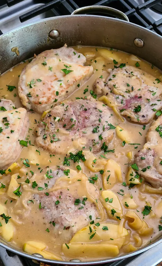 pork chops with apples in cider sherry sauce in skillet on stovetop