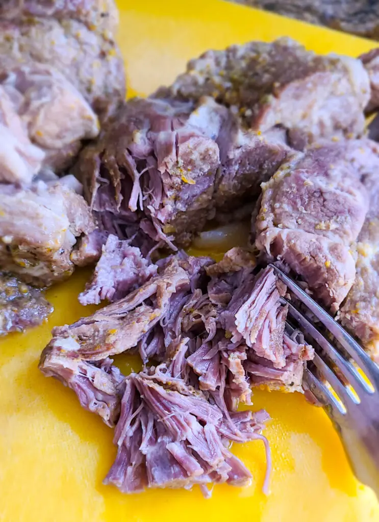shred pork butt with fork on a cutting board and discard the fatty piece