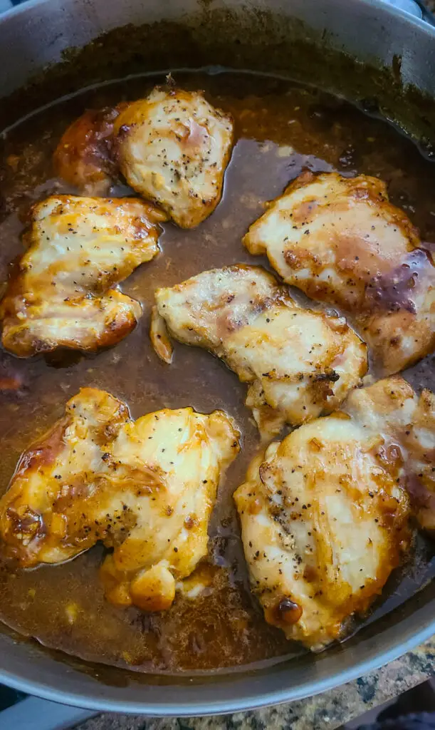 skillet with baked chicken thighs in peach bourbon bbq sauce