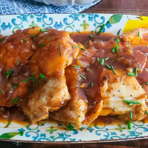 image of plated peach and bourbon bbq chicken garnished with fresh sliced peaches and sprinkled with snipped chives