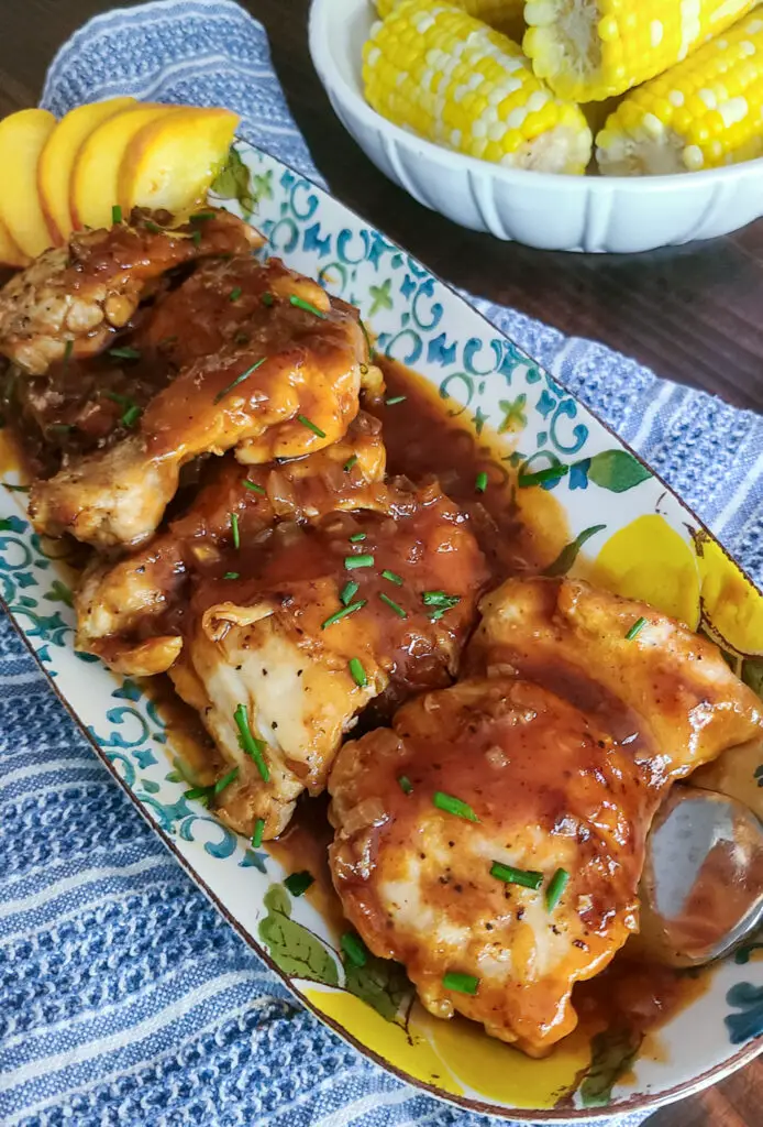 peach and bourbon bbq chicken on a platter with a side of corn