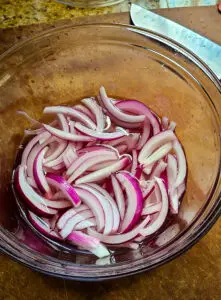 Sliced red onion in pickling liquid in bowl
