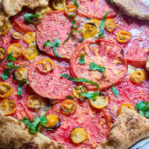baked Heirloom tomato galette on sheet pan garnished with fresh basil