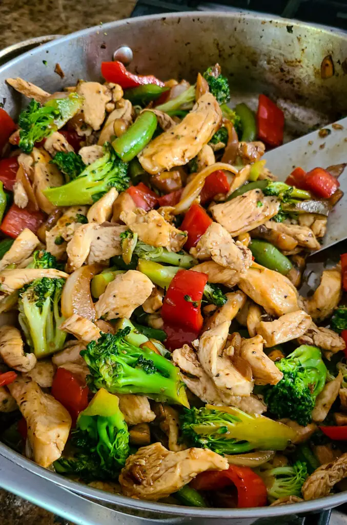 image of an Asain cuisine style chicken and vegetable stir-fry in a stainless steel skillet.