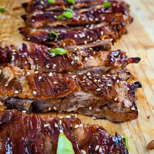 upclose image of Sticky Sweet Soy Spare Ribs sliced into separate ribs on wooden cutting board