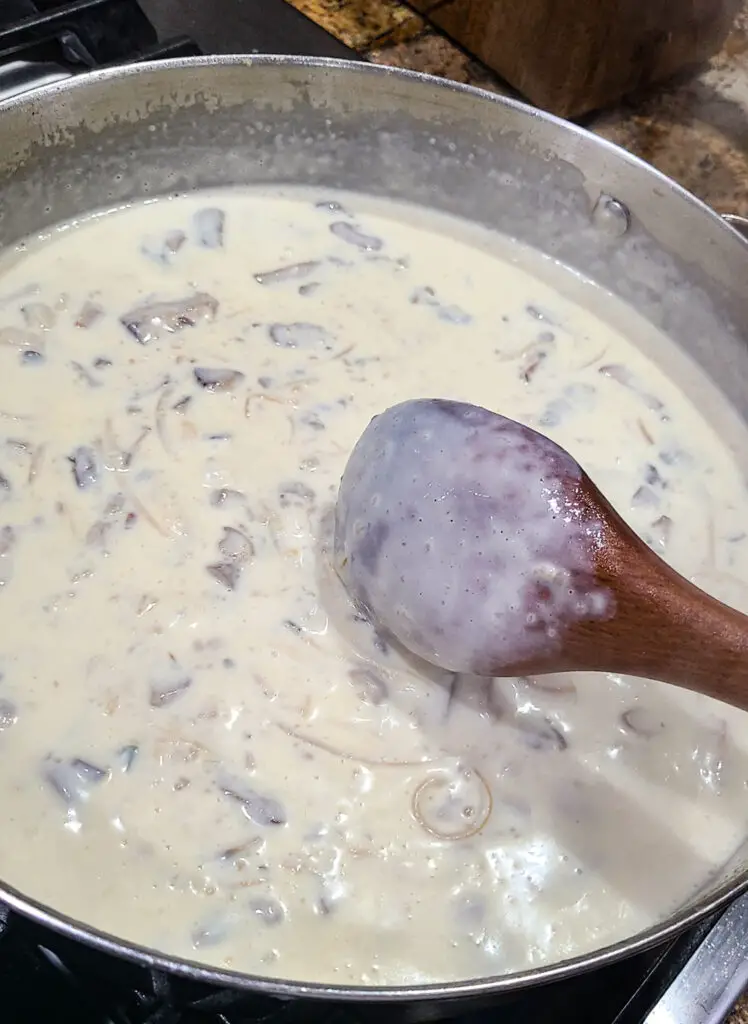 image of thickened cream sauce in skilled with wooden spoon coated with cream sauce