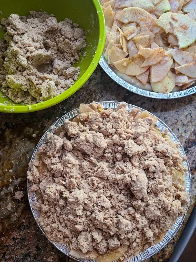 image of bowl of cinnamon crumbles, layered over sliced apples in cake pan