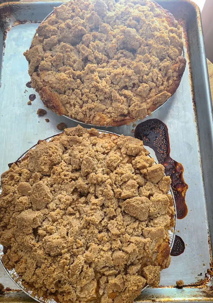 image of two pie pans on baking sheet containing fully baked apple cinnamon crumb cakes