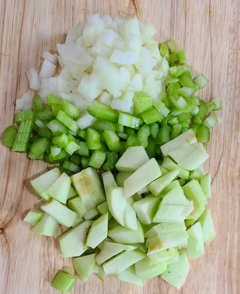 image of chopped onion, celery and apples on wooden cutting board