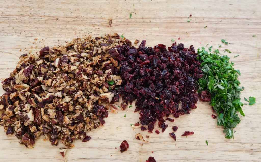 Chop remaining ingredients: dried cranberries, maple roasted pecans, rosemary, thyme, sage, and parsley