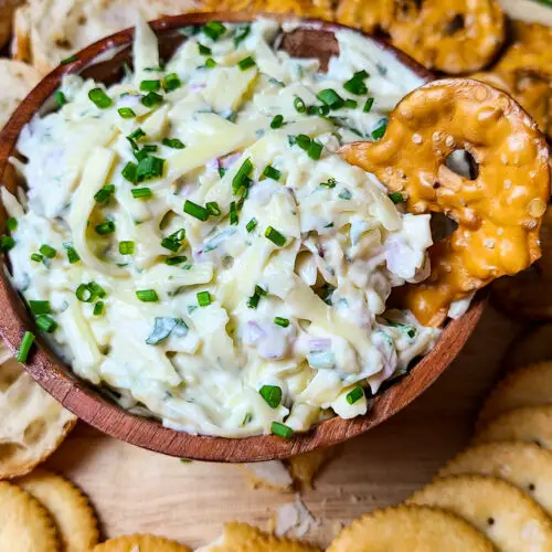 JARLSBERG CHEESE DIP in wooden bowl served with pretzels, crackers and sliced baguette