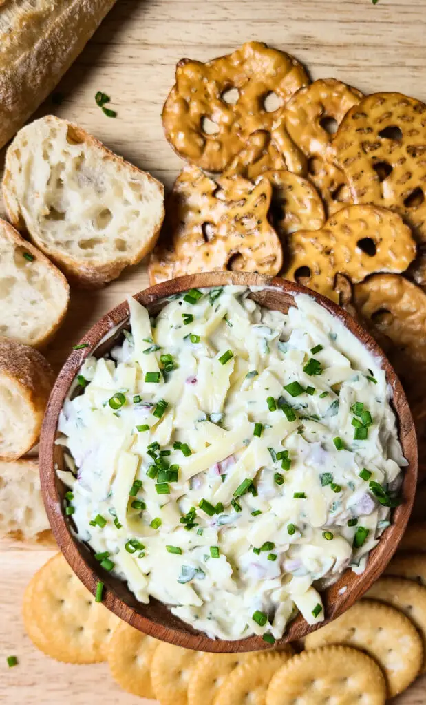 flatlay image of jarlsberg cheese dip in wooden bowl served with pretzels, baguette, and ritz crackers