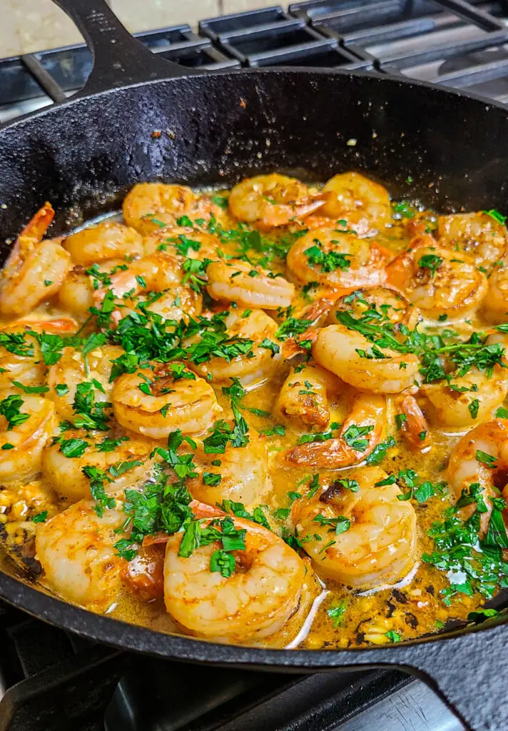 garlic butter shrimp in cast iron skillet, garnished with chopped parsley