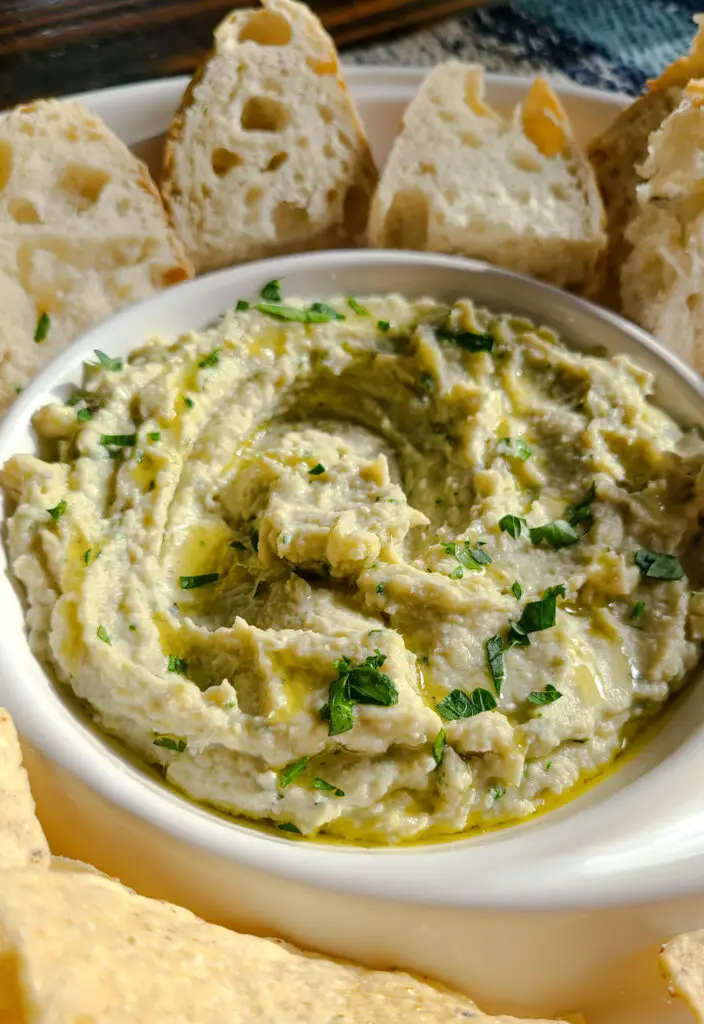 white bean artichoke and feta dip drizzled with olive oil and topped with chopped parsley