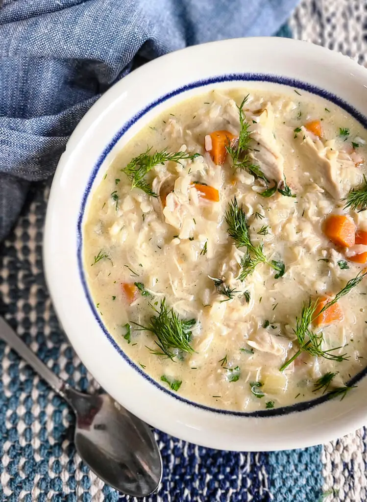 bowl of avgolemono soup garnished with sprigs of fresh dill