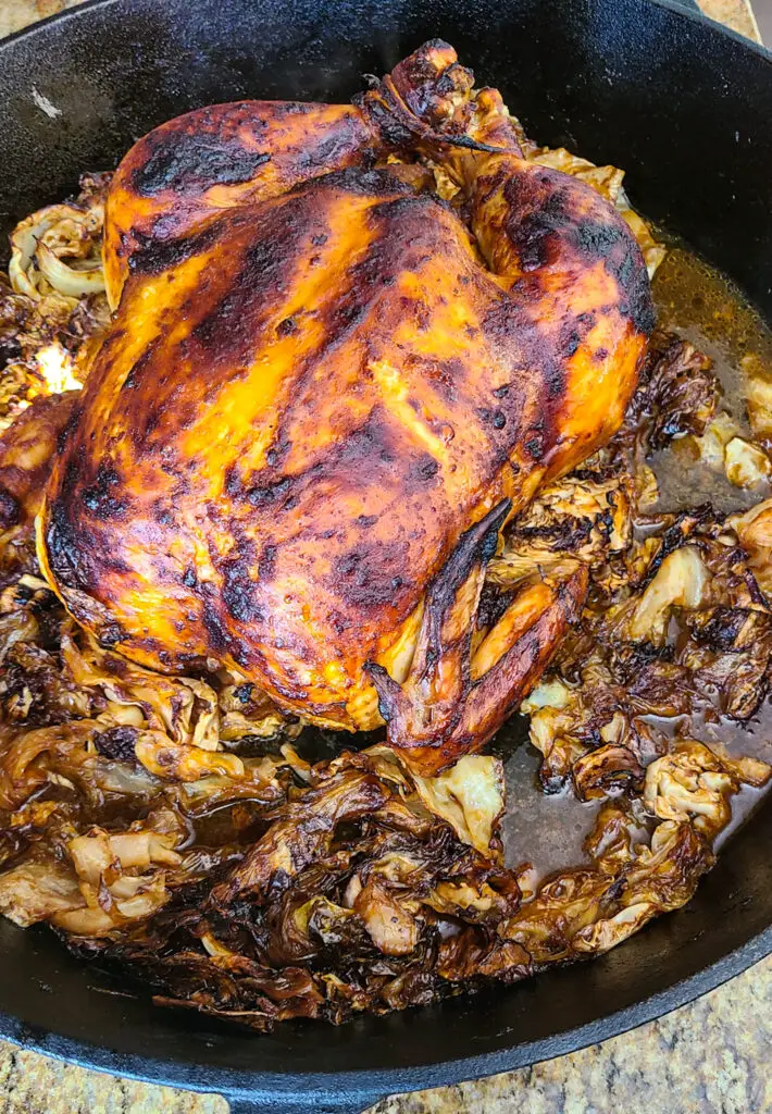 image of slow roasted gochujang chicken caramelized cabbage in cast iron skillet and cooking juices.