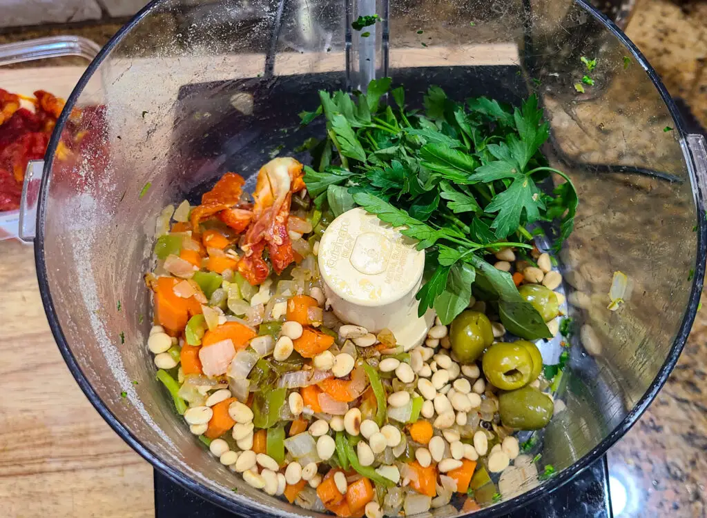Image of ingredients in a food processor for purpose of showing steps of how to make Italian style meatloaf
