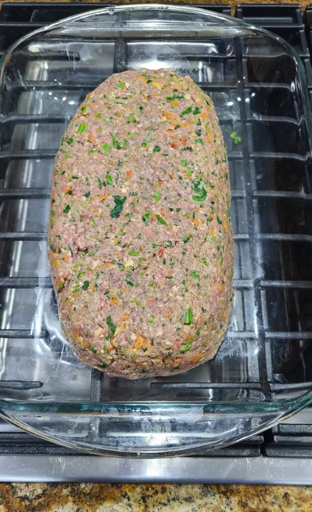 image of raw meatloaf mixture formed into rectangle shape in Pyrex baking dish