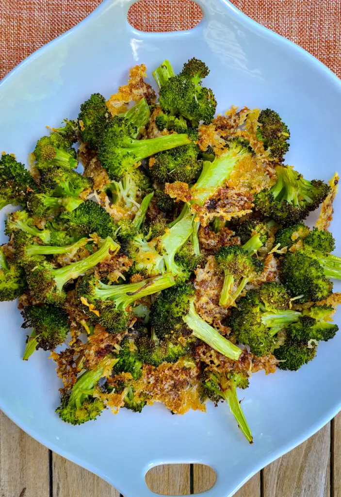overhead image of roasted broccoli with crispy parmesan and panko breadcrumb coating in shallow white serving dish