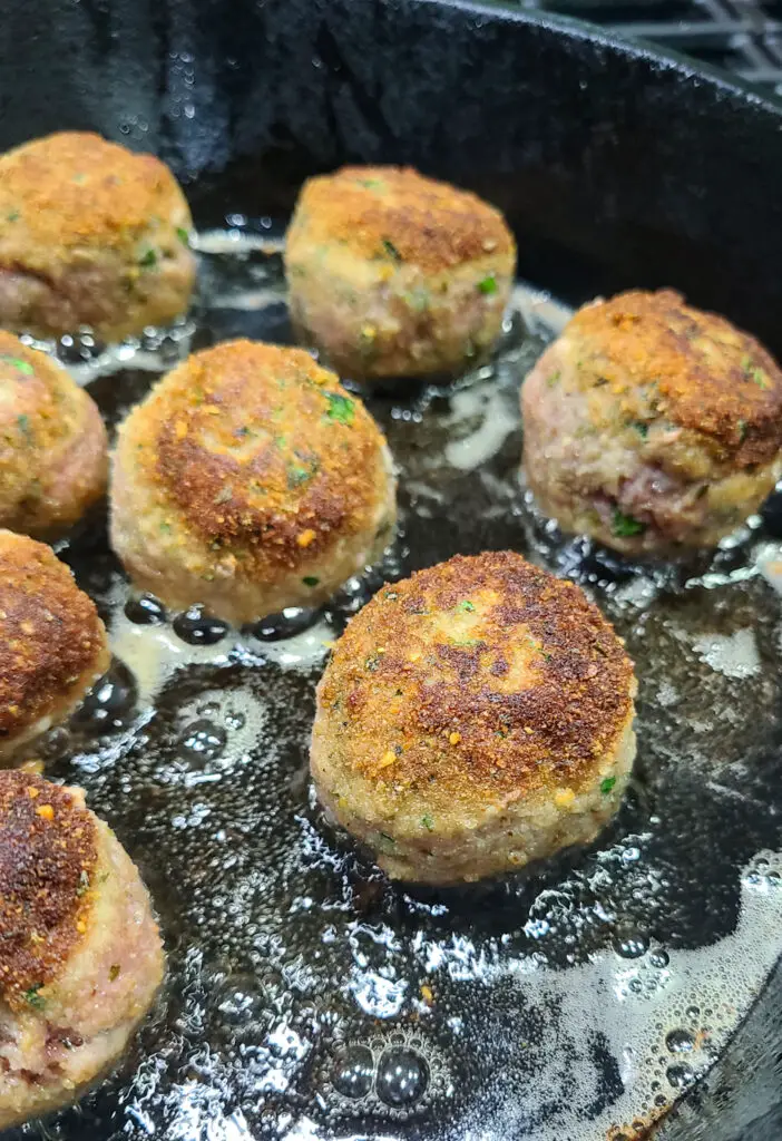 searing chicken piccata meatballs in olive oil in cast iron pan